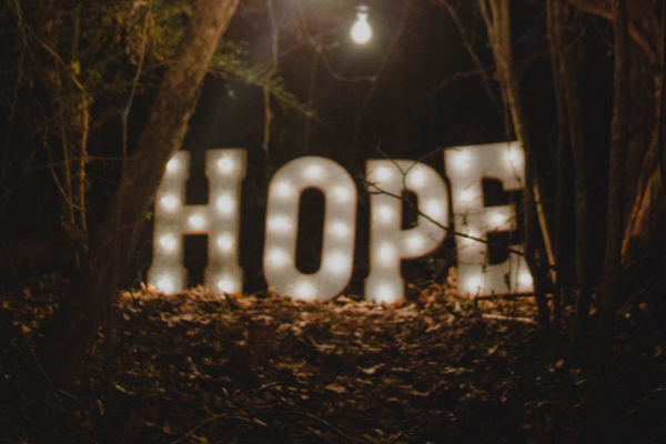 Illuminated HOPE sign in a wooded setting